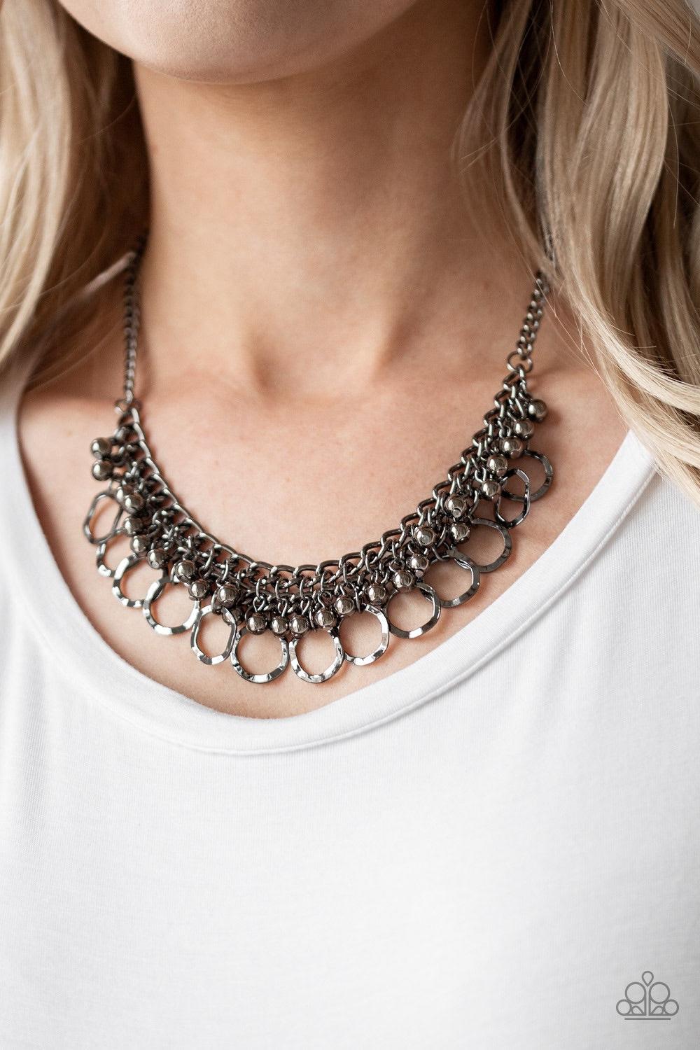 Paparazzi Accessories Ring Leader Radiance - Black Rows of shiny gunmetal beads and hammered gunmetal rings swing from the bottom of interlocking gunmetal chains, creating a bold fringe below the collar. Features an adjustable clasp closure. Jewelry