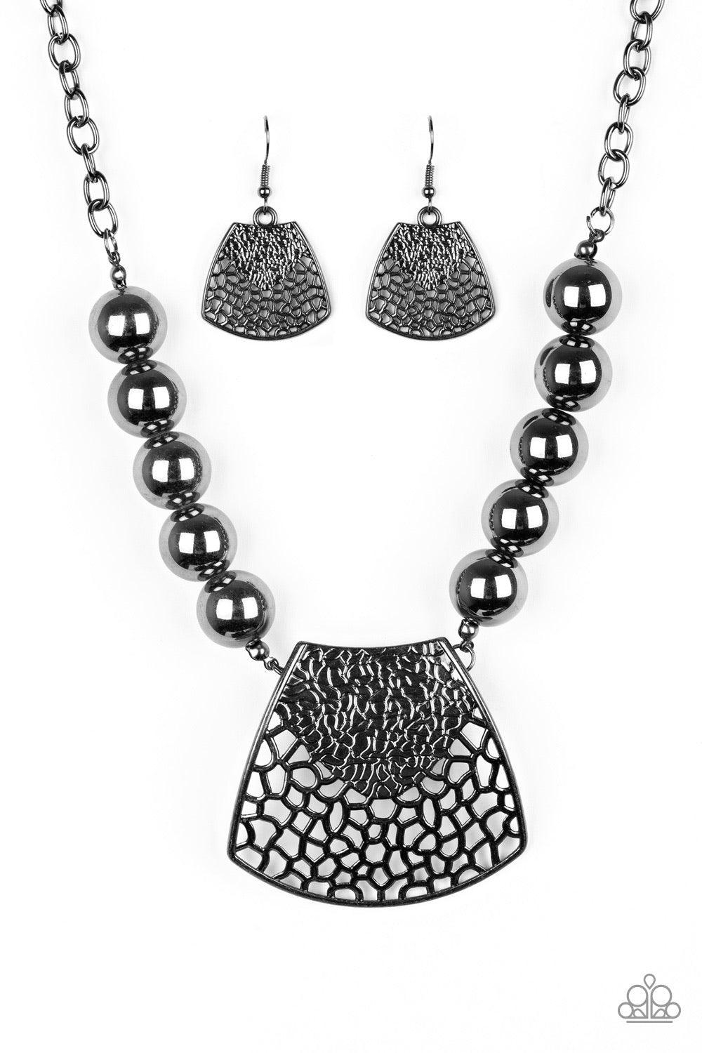Paparazzi Accessories Large And In Charge - Black Featuring ornately stenciled and embossed details, a flared gunmetal plate swings from a boldly gunmetal beaded chain below the collar for a fierce look. Features an adjustable clasp closure. Sold as one i
