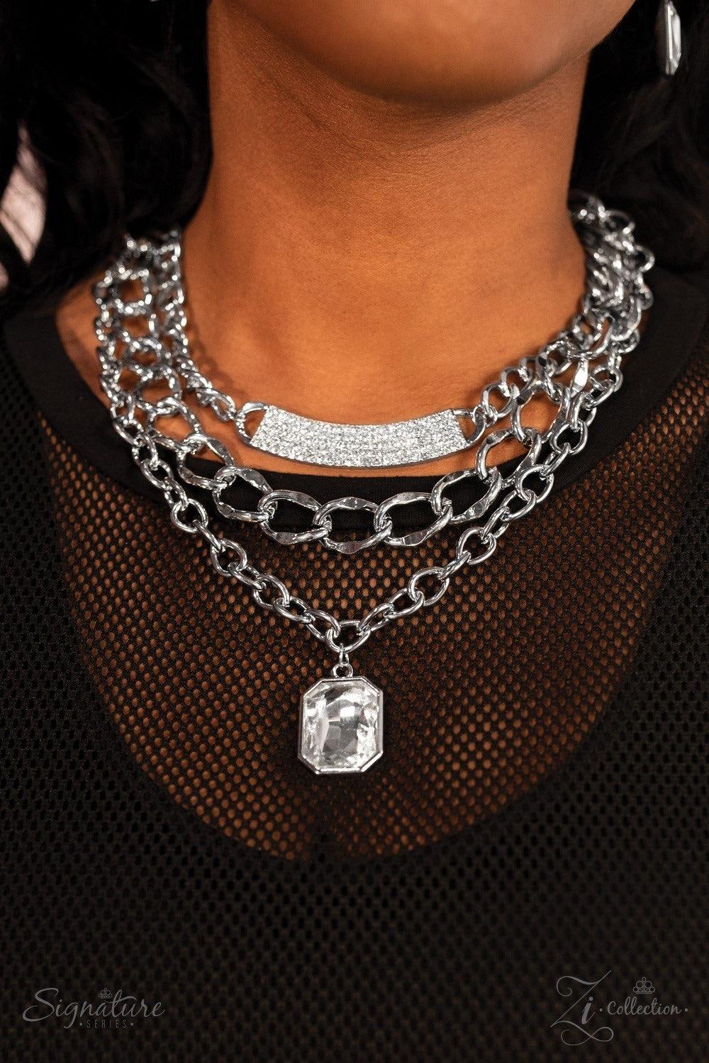 Paparazzi Accessories The Stacy A large emerald-cut rhinestone drips below a mashup of oversized silver chains, creating a beautiful contrast of industrial edge and timeless sparkle. A bowing silver bar encrusted in dazzling white rhinestones adorns the t