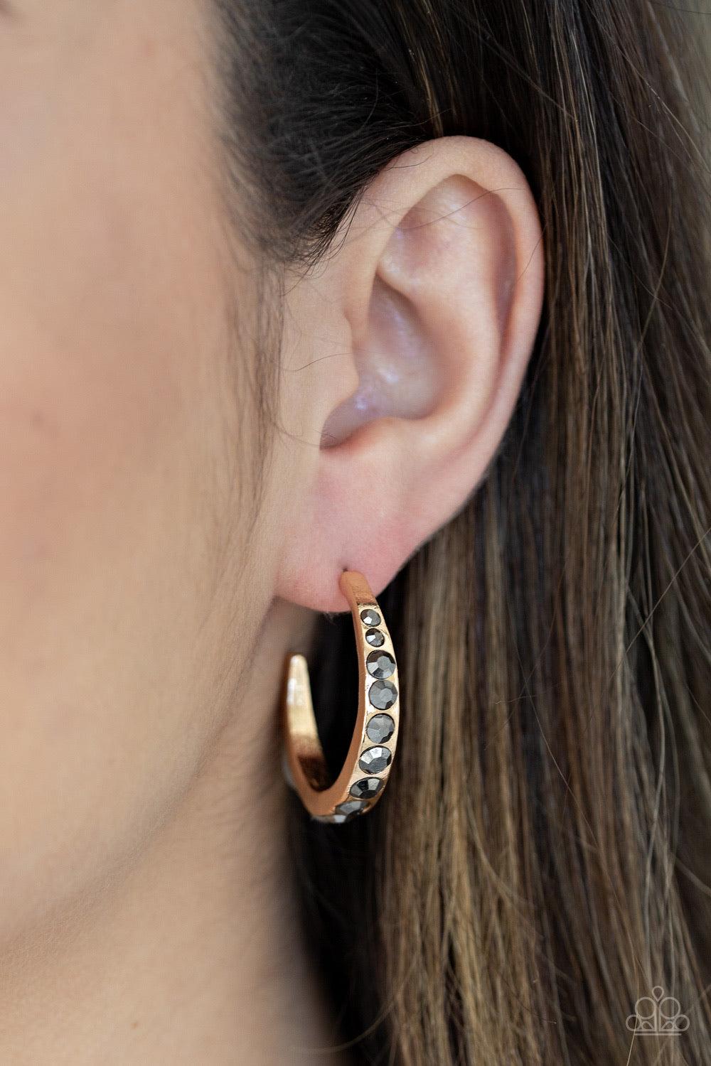 Paparazzi Accessories Welcome To Glam Town ~Gold Gradually increasing in size near the center, glassy hematite rhinestones are encrusted down the spine of a dainty gold hoop for a grunge-glamorous look. Earring attaches to a standard post fitting. Hoop me