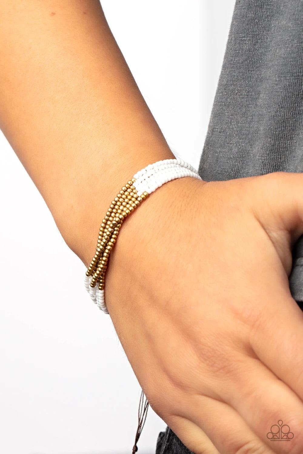 Paparazzi Accessories BEAD Bold - White Four strands of white seed beads accented with a bold section of brass seed beads wraps around the wrist for a simple yet trendy look. Features an adjustable sliding knot closure. Sold as one individual bracelet. Je
