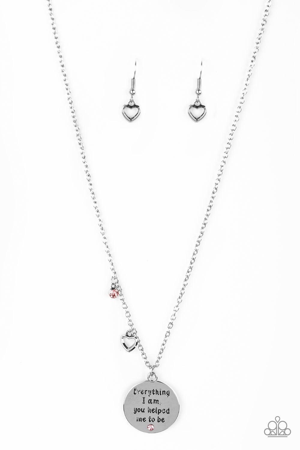 Paparazzi Accessories Everything I Am - Pink A solitaire pink rhinestone, dainty silver heart, and a shimmery silver disc stamped with the inspirational phrase, "Everything I am, you helped me to be", swings below the collar for a whimsical look. Features