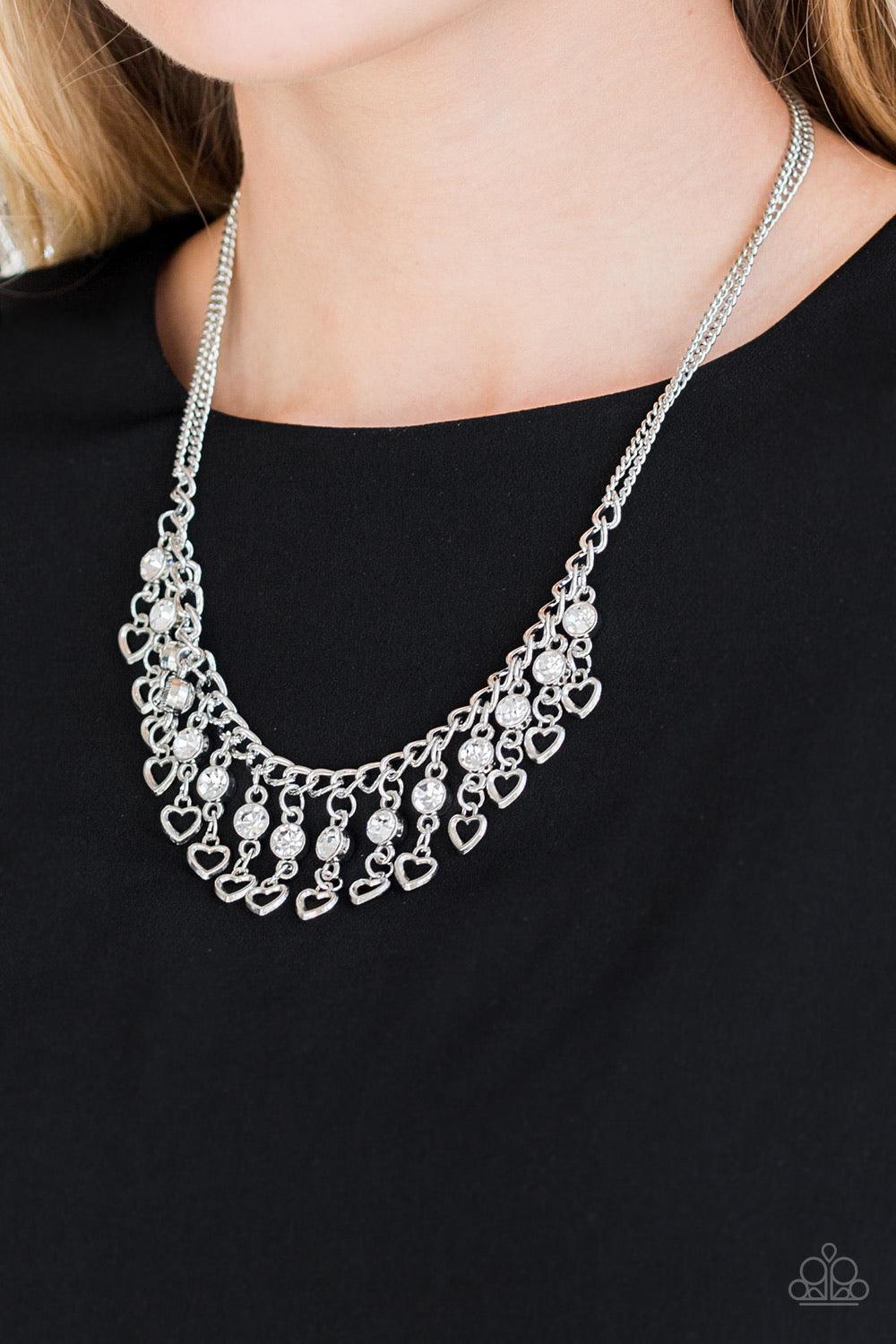 Paparazzi Accessories Valentines Day Drama ~White A row of shimmery silver hearts and glittery white rhinestones swing from the bottom of a glistening silver fringe, creating a flirty fringe below the collar. Features an adjustable clasp closure. Sold as