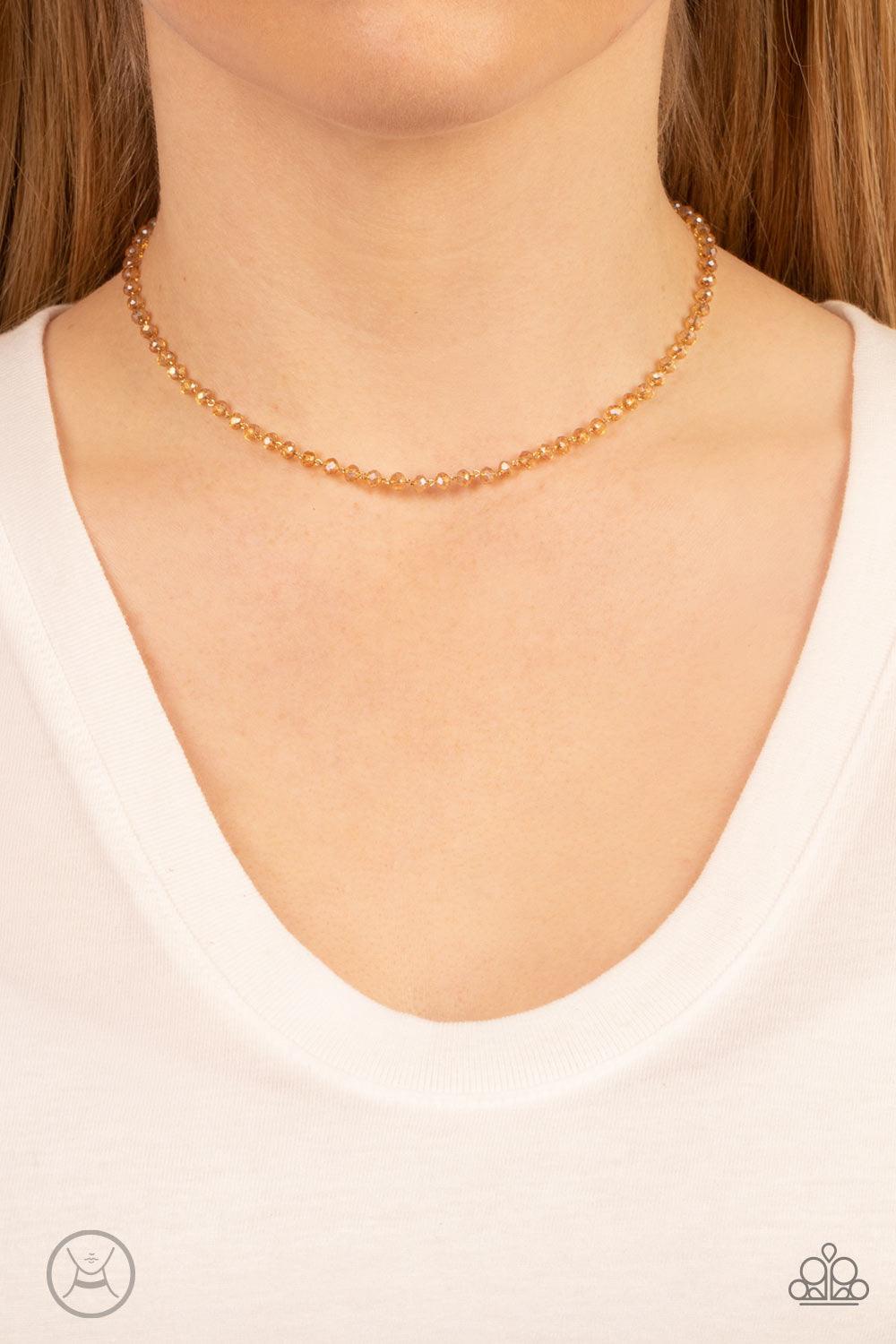Paparazzi Accessories Mini MVP - Gold A dainty row of faceted white crystal-like beads delicately links around the neck, resulting in a golden glimmer. Features an adjustable clasp closure. Sold as one individual choker necklace. Includes one pair of matc