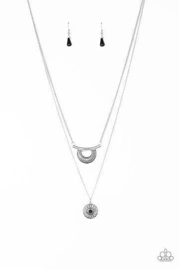 Paparazzi Accessories Gypsy Go-Getter - Black Radiating with linear patterns, a shimmery silver frame swings from the uppermost chain above a silver disc radiating with floral detail. A dainty black bead dots the center of the lowermost pendant for a colo