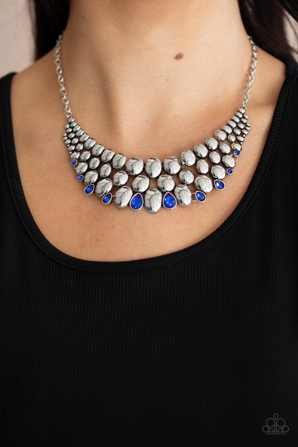 Paparazzi Accessories Powerhouse Party - Blue Gradually increasing in size at the center, a shiny collection of antiqued silver ovals join into bubbly plates that interlock below the collar. Dainty round and teardrop French Blue rhinestones dot the bottom