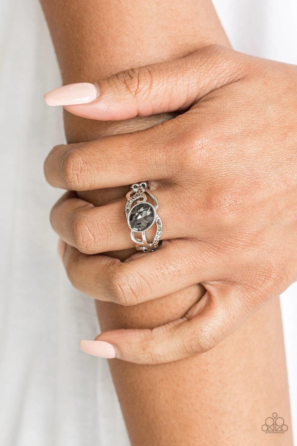 Paparazzi Accessories Couldn’t Care FLAWLESS - Silver Encrusted in sections of dainty hematite rhinestones, shimmery silver filigree curls around a smoky rhinestone center for a refined flair. Features a dainty stretchy band for a flexible fit. Sold as on