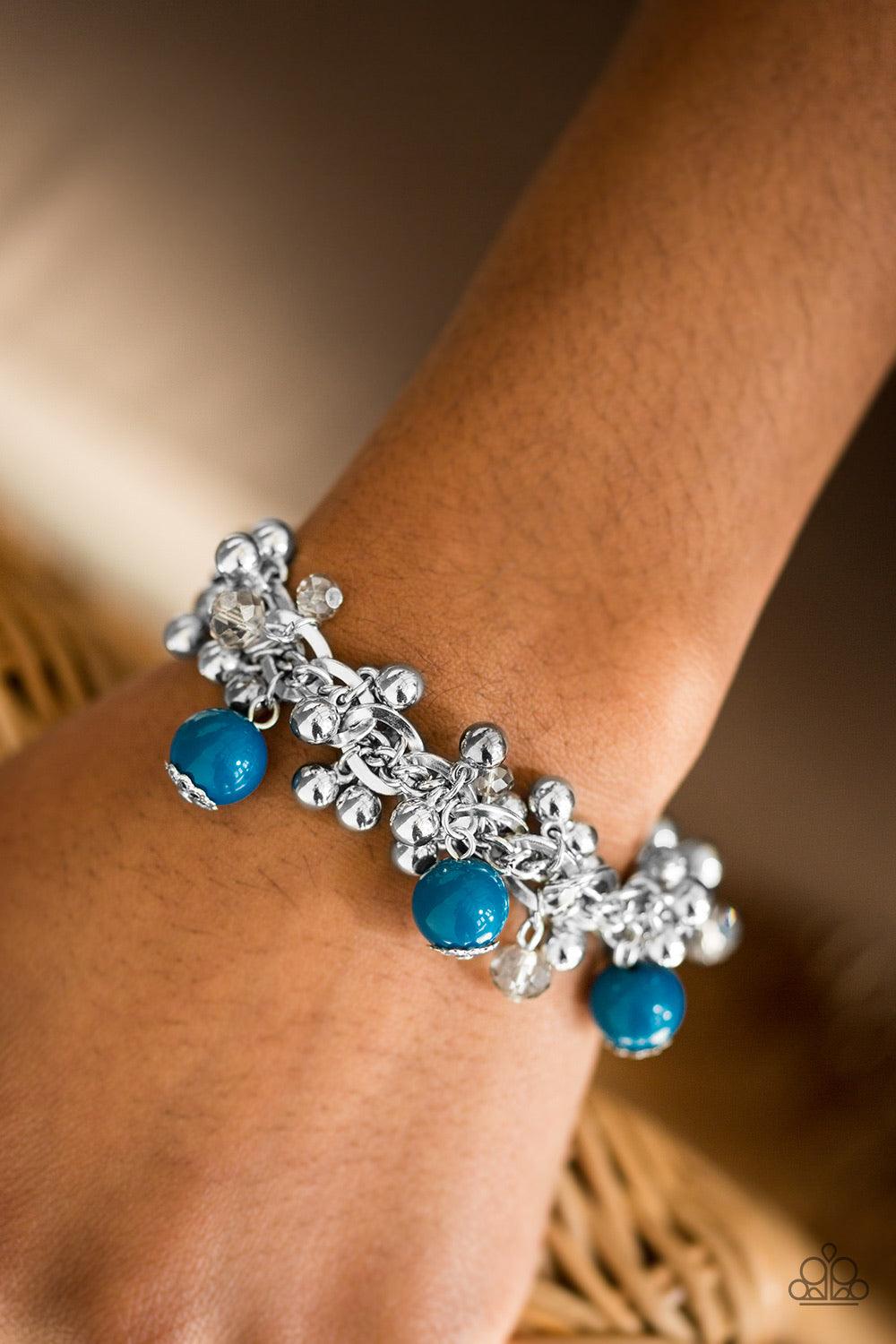 Paparazzi Accessories Pretty In Posh - Blue Crystal like beads and classic silver beads dangle from a bold silver chain, creating a clustered fringe around the wrist. Polished blue beads trickle between the clustered beading, adding a casual pop of color