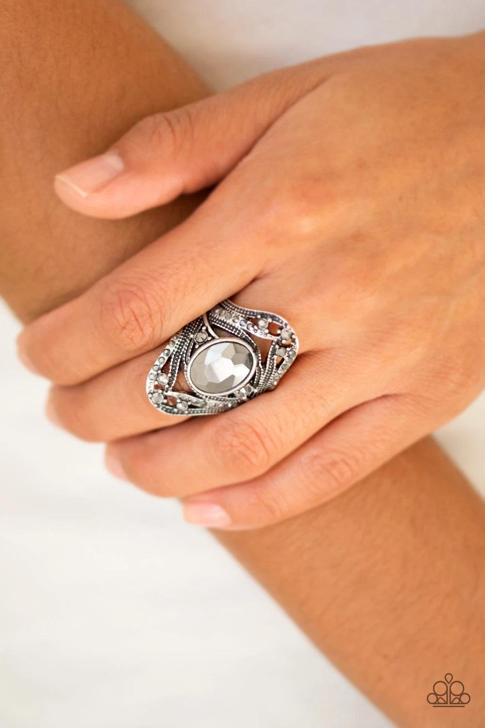 Paparazzi Accessories Red Carpet Rebel - Silver Radiating with dainty hematite rhinestones, studded silver bands whirl across the finger, coalescing into an ornate frame. An over sized hematite rhinestone is pressed into the center of the band for a drama