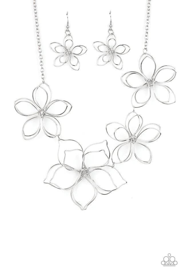 Paparazzi Accessories Flower Garden Fashionista - Silver Shiny silver wire delicately twists into oversized blossoms. Varying in size, the airy floral frames delicately link into an asymmetrical display as the layered frames elegantly pop beneath the coll