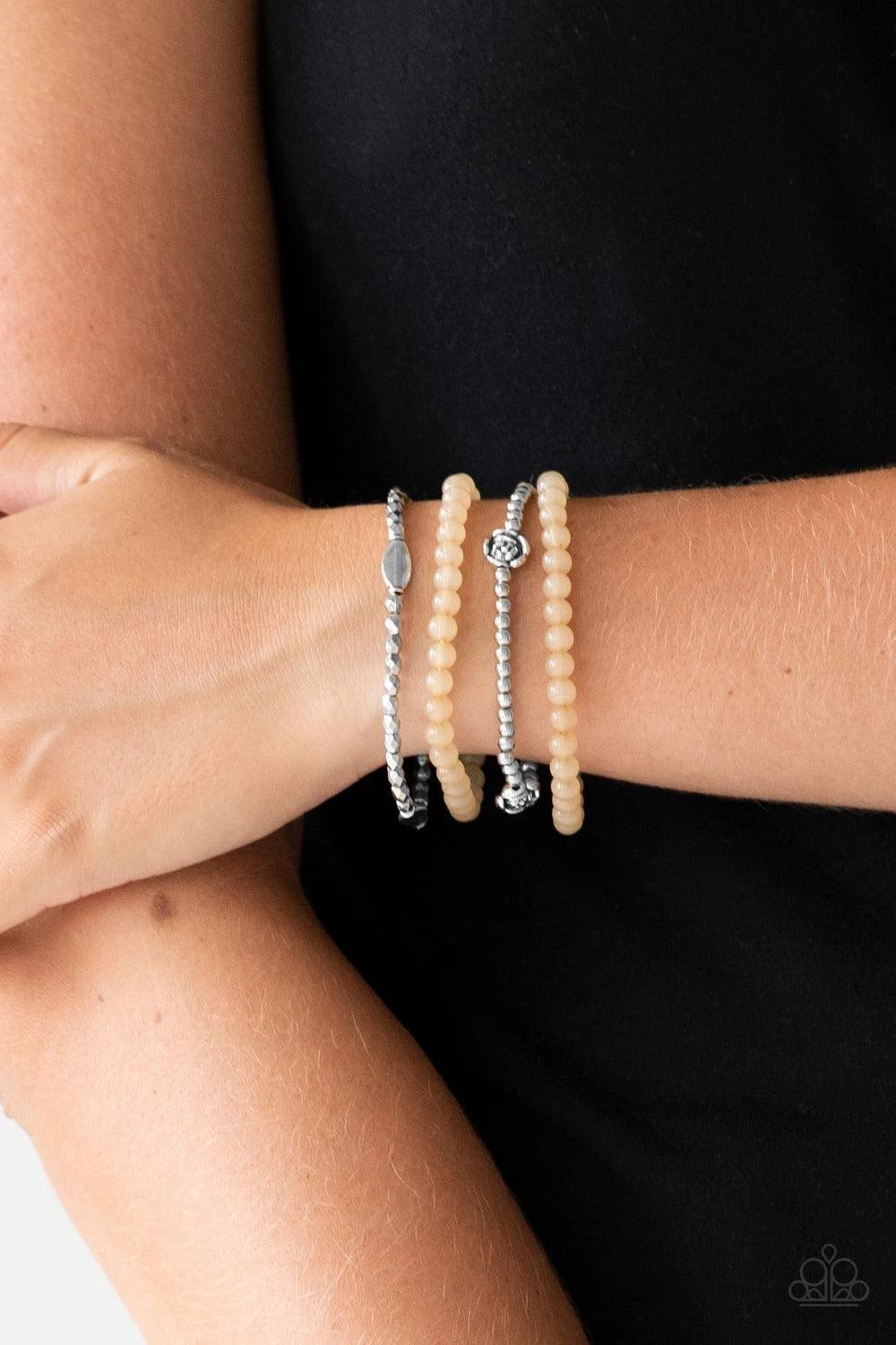 Paparazzi Accessories Blooming Buttercups - Brown Mismatched silver beads and strands of glassy brown beads are threaded along stretchy bands. Infused with silver accents, dainty rose blossoms adorn the wrist for a seasonal finish. Sold as one set of four