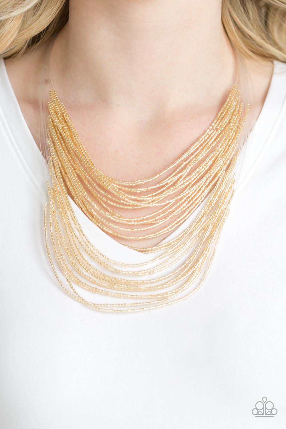 Paparazzi Accessories Catwalk Queen - Gold Strand after strand of metallic gold seed beads fall together to create a bold statement piece. Features an adjustable clasp closure. Sold as one individual necklace. Includes one pair of matching earrings. Jewel