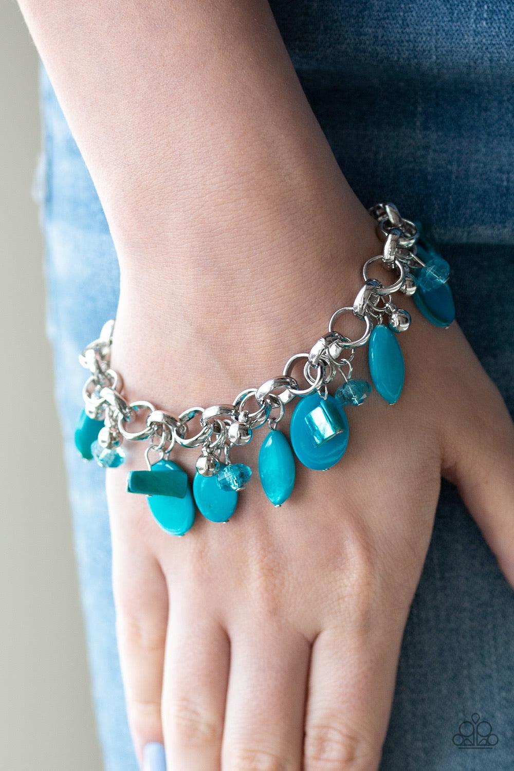 Paparazzi Accessories Seashore Sailing - Bracelet A collection of blue shell-like beads, blue crystal-like beads, and shiny silver beads swing from a bold silver chain, creating a whimsical fringe around the wrist. Features an adjustable clasp closure. Je
