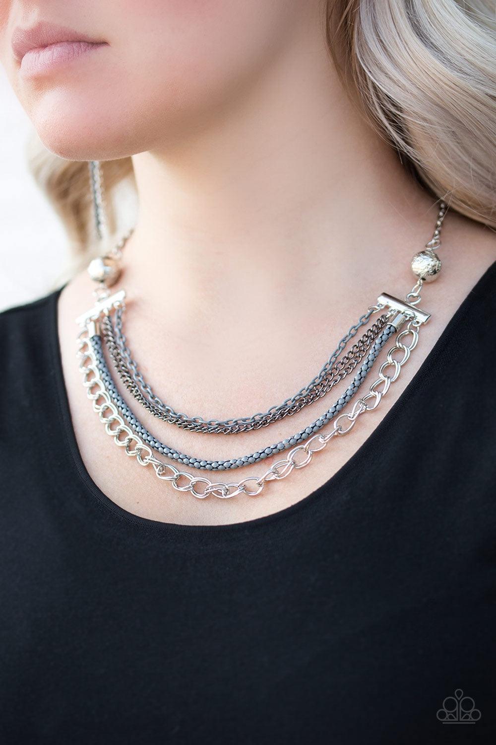 Paparazzi Accessories High-Intensity - Silver Two floral silver beads give way to an array of gray, gunmetal, and silver chains. Strung between two metal beads, the mismatched chains layer below the collar in a colorfully industrial fashion. Features an a