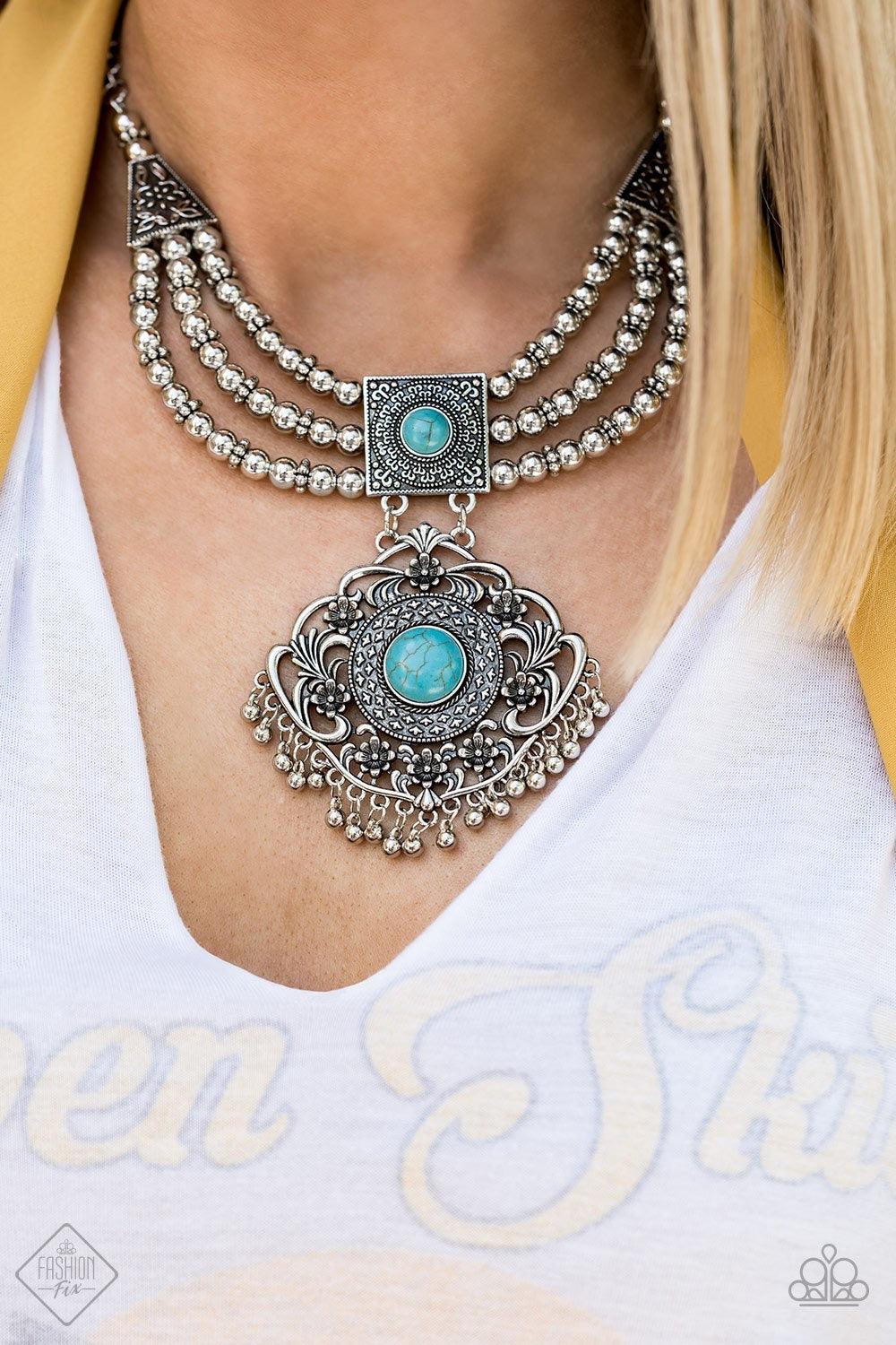 Paparazzi Accessories Santa Fe Solstice - Blue A vintage inspired pendant adorned in intricate studded textures and bordered by a shiny fringe of silver beads attaches to a squared frame rich in detail. Turquoise stones dot each anchoring piece, bringing