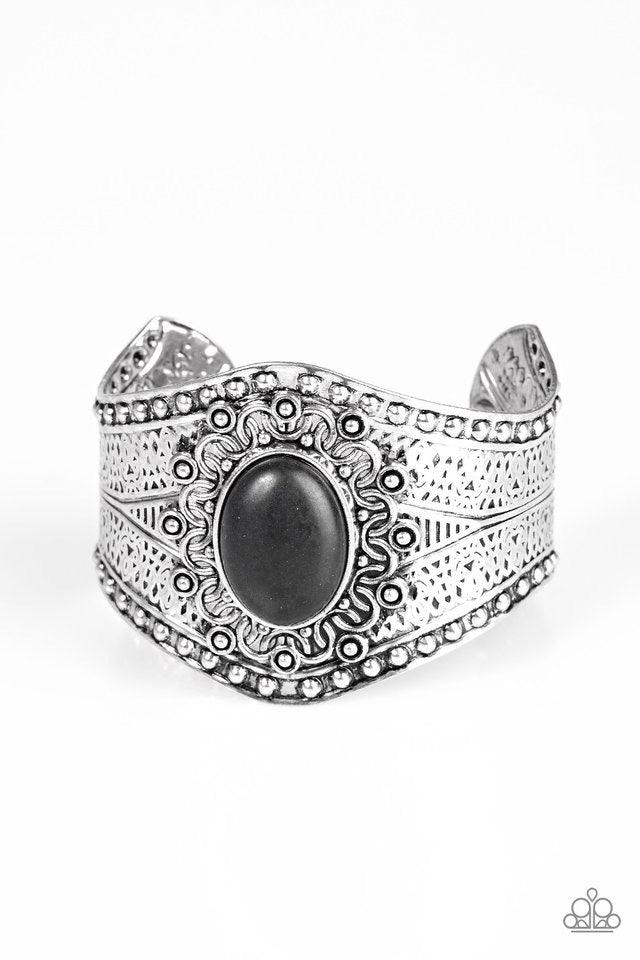 Paparazzi Accessories Mojave Majesty - Black Delicately hammered and studded in tribal inspired textures, a thick silver cuff wraps around the wrist in an artisan inspired fashion. A smooth black stone is pressed into the middle of a silver sunburst patte