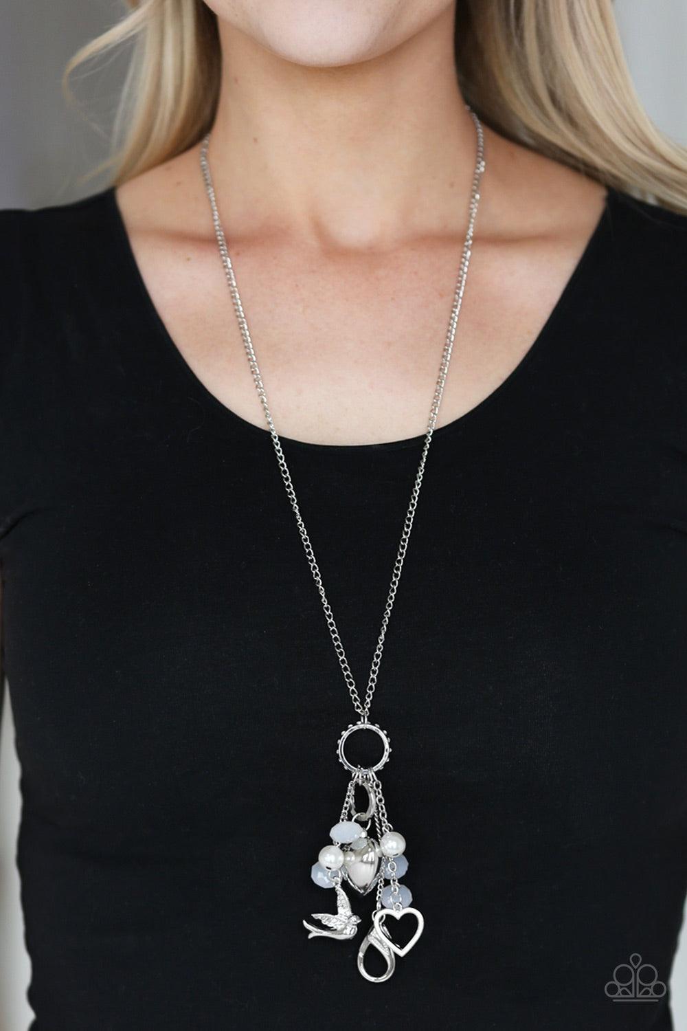 Paparazzi Accessories I Will Fly - White A silver bird charm, silver heart charms, and collection of white pearls and opaque crystal-like beads swing from the bottom of a lengthened silver chain for whimsically clustered look. A lobster clasp hangs from t