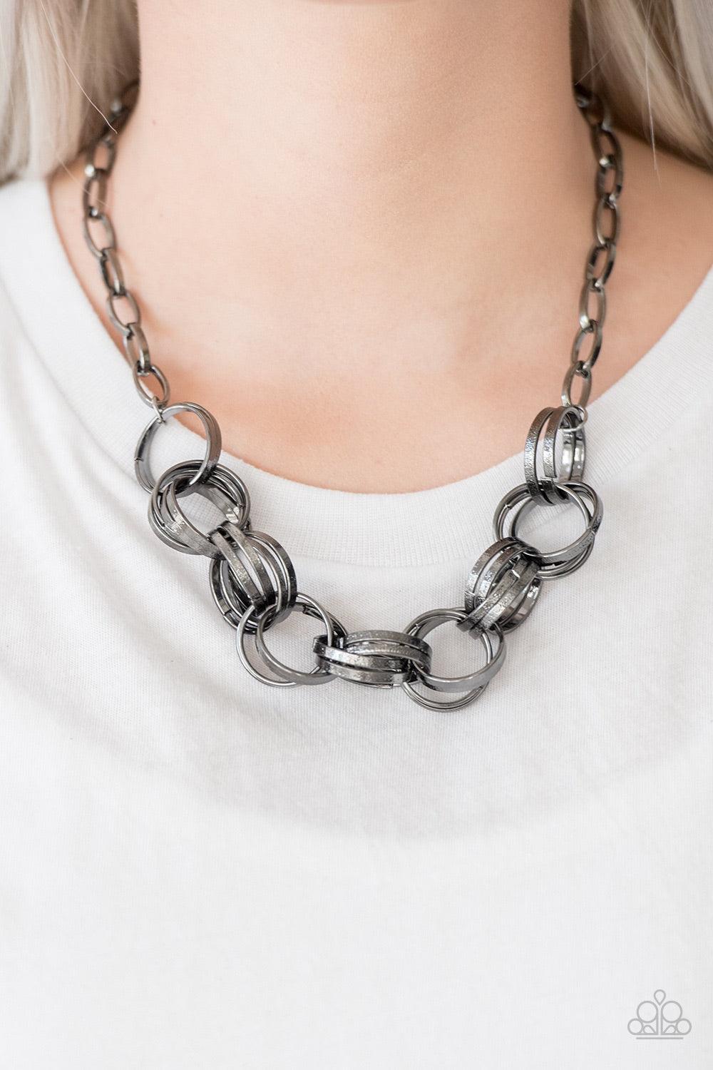 Paparazzi Accessories Statement Made - Black Etched in light-catching shimmer, glistening gunmetal rings link below the collar, connecting into a bold clustered fringe for a fierce industrial look. Features an adjustable clasp closure. Jewelry