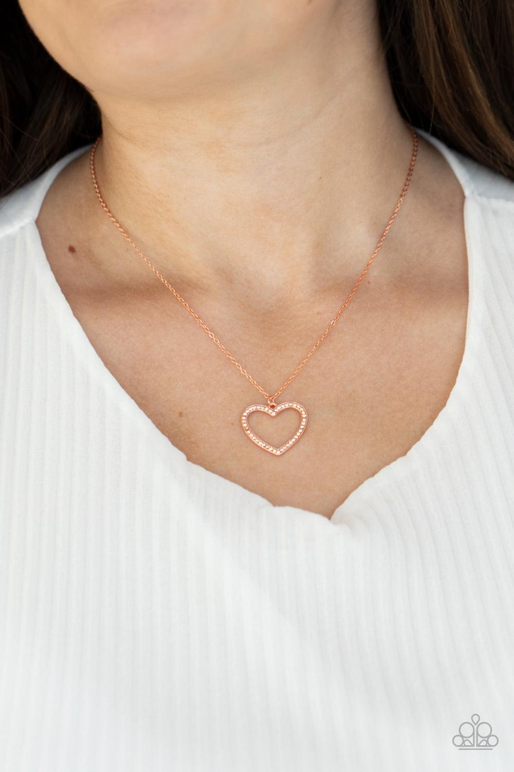 Paparazzi Accessories GLOW By Heart - Copper Encrusted in sparkly rhinestones, an airy shiny copper heart frame swings from a dainty shiny copper chain below the collar for a romantic look. Features an adjustable clasp closure. Sold as one individual neck
