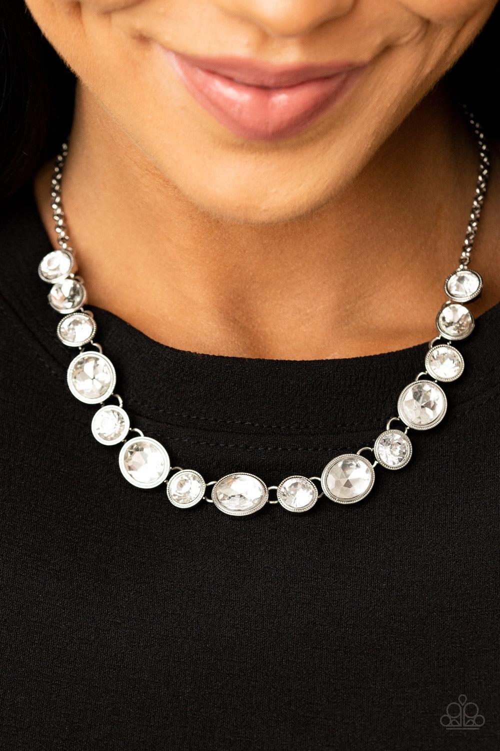Paparazzi Accessories Girls Gotta Glow - White Encased in sleek silver frames, oval and round white rhinestones alternate below the collar for a timeless look. Features an adjustable clasp closure. Sold as one individual necklace. Includes one pair of mat