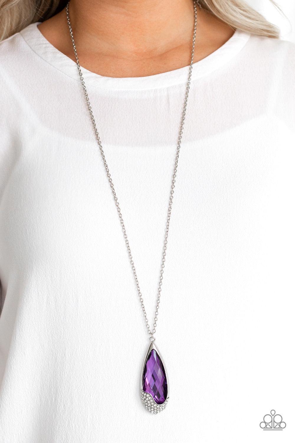Paparazzi Accessories Spellbound - Purple An oversized purple teardrop gem is nestled inside of an abstract silver frame that has been dipped in glassy white rhinestones. The spellbinding pendant swings from the bottom of a lengthened silver chain for a g