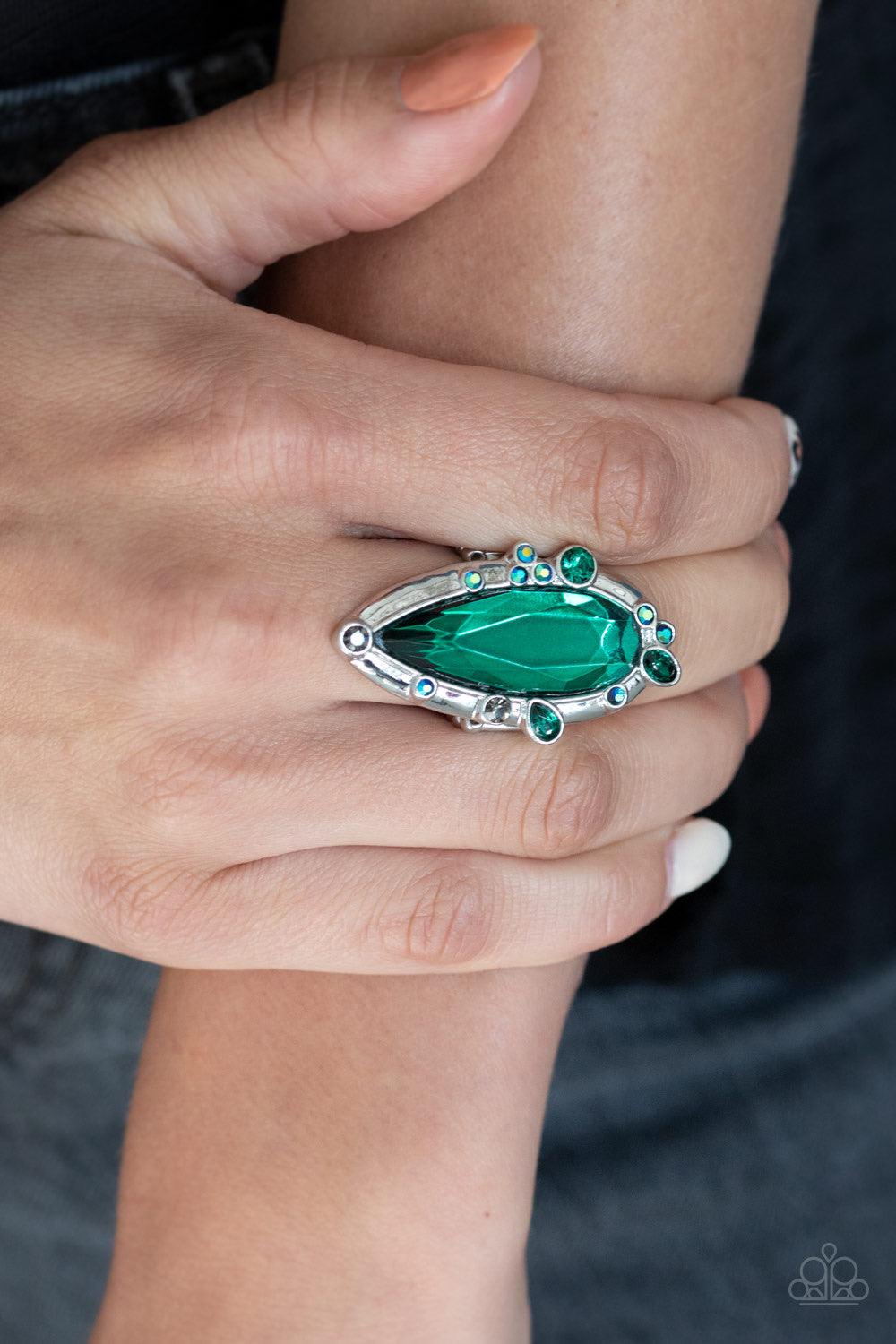 Paparazzi Accessories Sparkle Smitten - Green Varying in color and shape, mismatched green iridescent rhinestones sporadically dot the front of a shiny silver teardrop frame. Featuring a flashy faceted surface, an oversized green teardrop gem adorns the c