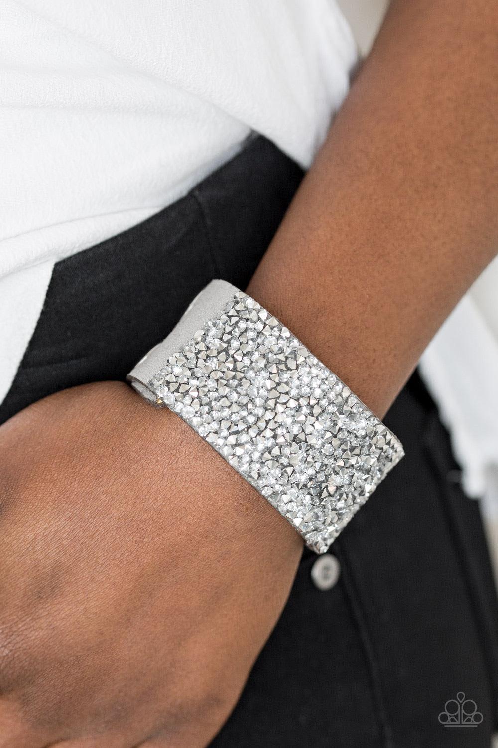 Paparazzi Accessories More Bang For Your Buck - Silver Featuring edgy prism style cuts, flashy metallic and glassy white rhinestones are sprinkled along a sparkling gray suede band, creating blinding shimmer. Features an adjustable snap closure. Sold as o