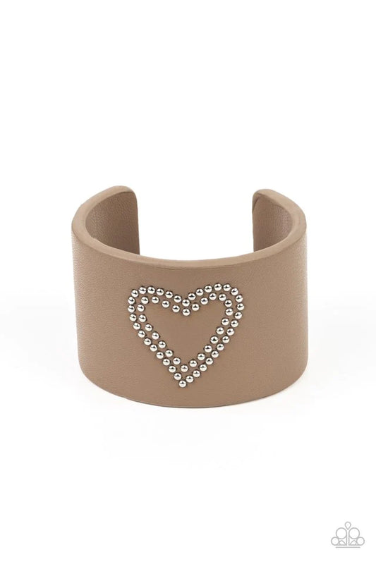 Paparazzi Accessories Rodeo Romance - Brown The center of a brown leather cuff is studded in a charming heart pattern, creating a rustically romantic look around the wrist. Jewelry