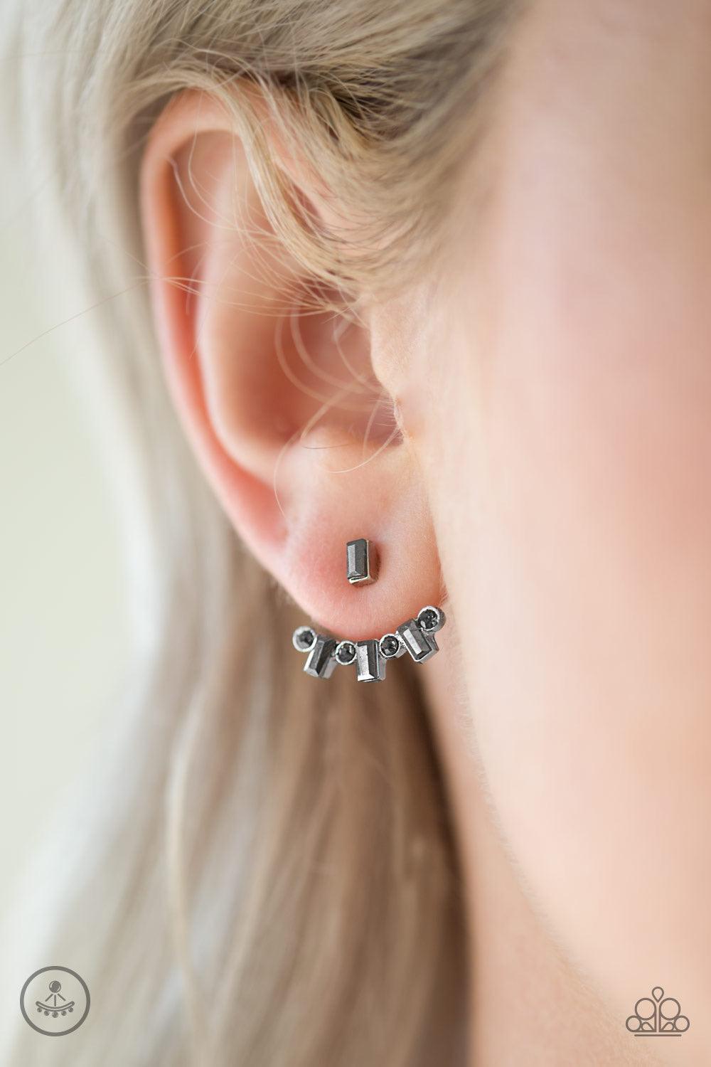 Paparazzi Accessories Courageously Cosmo - Silver A hematite emerald-cut rhinestone attaches to a double-sided post, designed to fasten behind the ear. Brushed in a high-sheen shimmer, the smoky rhinestone encrusted double-sided post peeks out beneath the