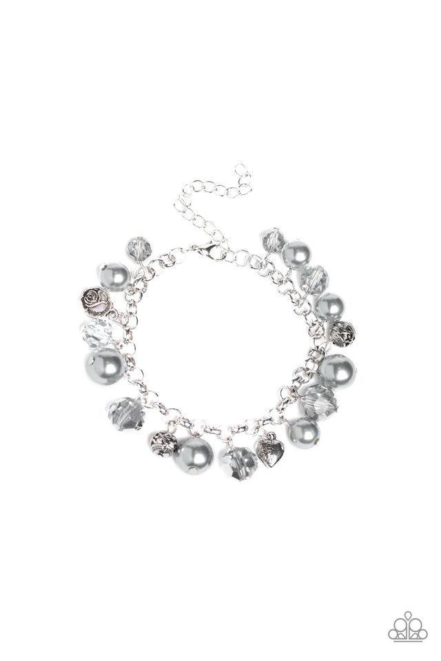 Paparazzi Accessories Cupid Couture - Silver Featuring a dainty silver heart charm, rose charm, and ornate silver beads, a refined collection of white pearls and metallic crystal-like beads swing from the wrist for a flirtatious flair. Features an adjusta