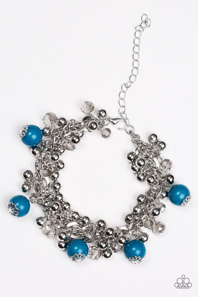 Paparazzi Accessories Pretty In Posh - Blue Crystal like beads and classic silver beads dangle from a bold silver chain, creating a clustered fringe around the wrist. Polished blue beads trickle between the clustered beading, adding a casual pop of color