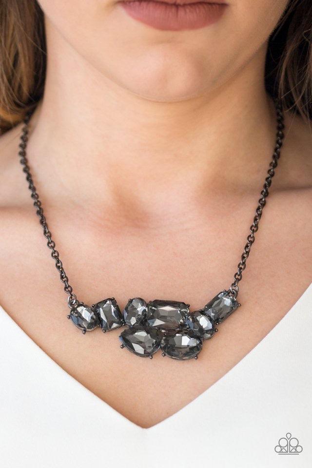 Paparazzi Accessories Urban Dynasty - Black Featuring regal teardrop, oval, and emerald style cuts, glittery gems coalesce into a glittery asymmetrical pendant below the collar, creating a knockout pendant. Features an adjustable clasp closure. Sold as on