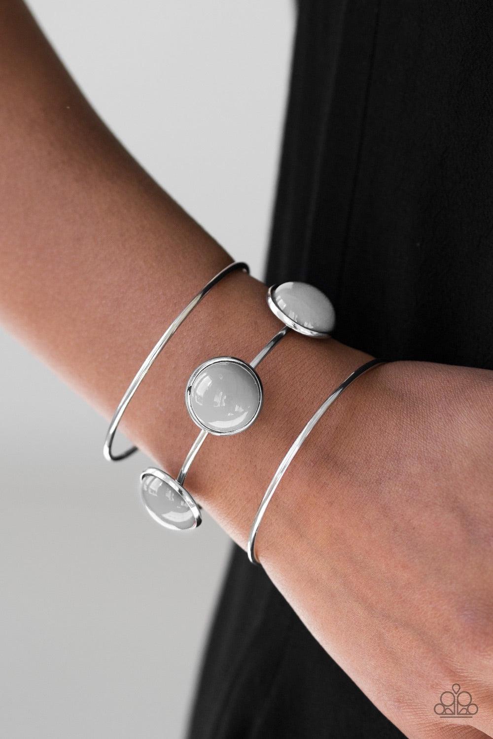 Paparazzi Accessories Lush Lagoon - Silver Three shimmery silver bars arc across the wrist, coalescing into an airy cuff. Three neutral gray beads are pressed into the centermost bar for a bubbly finish. Jewelry