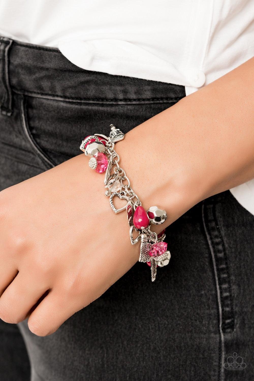 Paparazzi Accessories Completely Innocent - Pink A collection of faceted silver beads, polished pink beads, and pink and white crystal-like beads swing from a shimmery silver chain. An assortment of charms, including hearts, feathers, and tassels dangle b