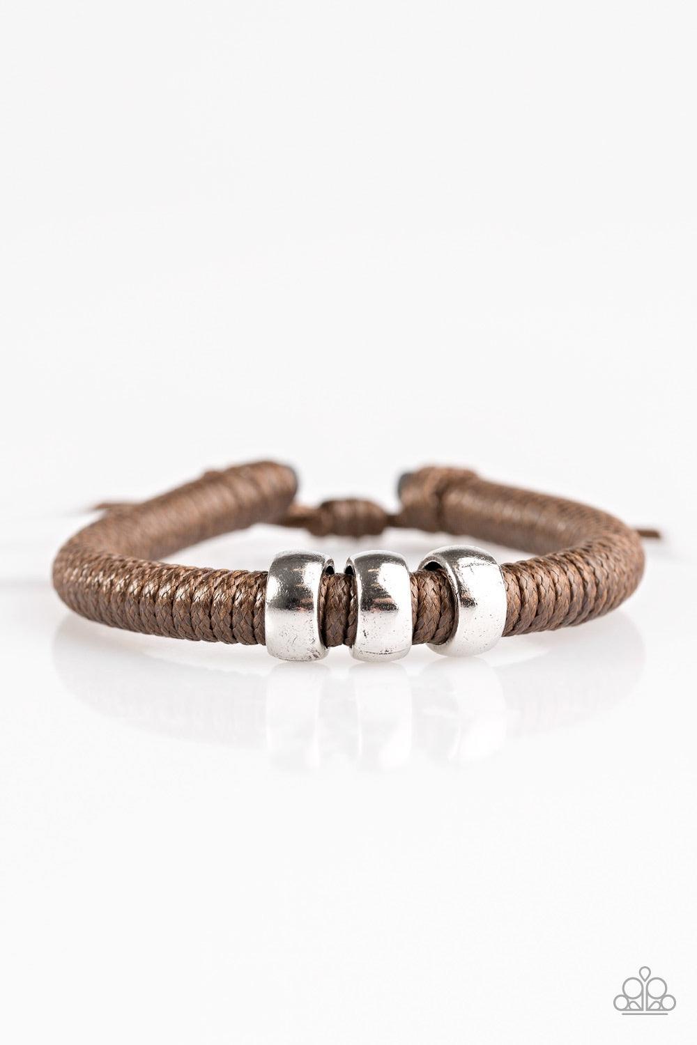 Paparazzi Accessories One For The Trail - Brown Shiny brown twine wraps around a black cord, creating an urban look around the wrist. Shiny silver beads slide along the cording for a rugged finish. Features an adjustable sliding knot closure. Jewelry