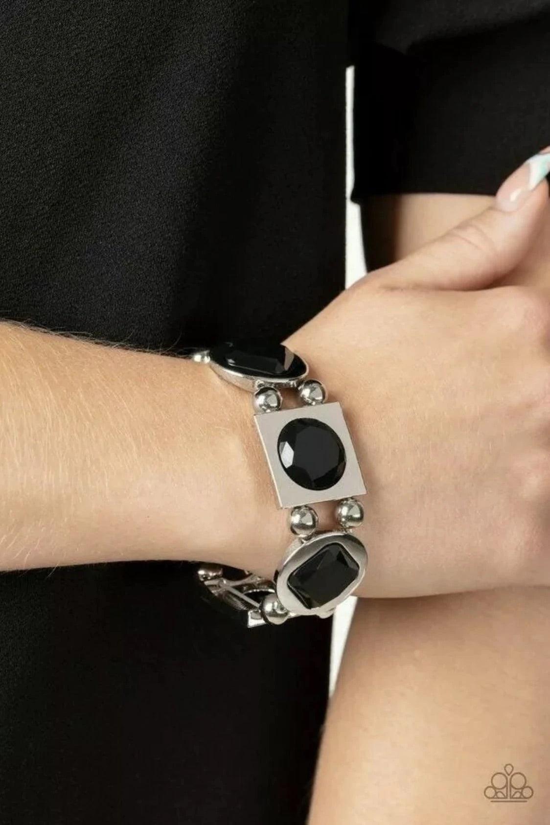 Paparazzi Accessories Asymmetrical A-Lister - Black Infused with pairs of silver beads, a faceted collection of round and square black gems are pressed into matching silver frames as they glide along stretchy bands around the wrist for a refined fashion.