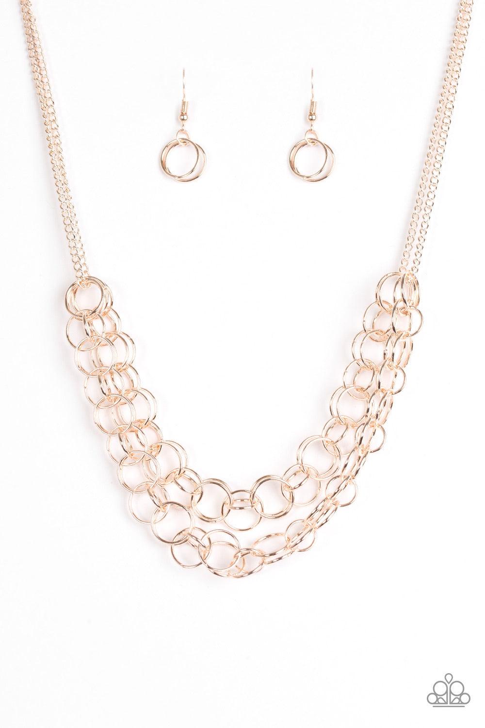 Paparazzi Accessories Circus Tent Tango - Gold Varying in size, rows of shiny rose gold rings interlock into two layered rows below the collar for an edgy industrial look. Features an adjustable clasp closure. Sold as one individual necklace. Includes one