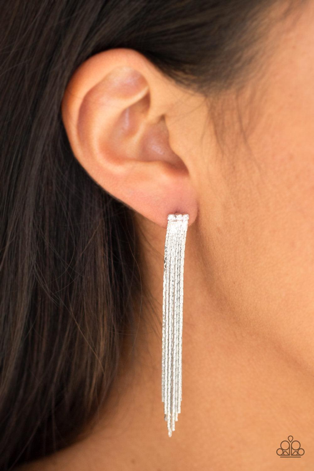 Paparazzi Accessories Night At The Oscars - White A tassel of flat silver chain cascades from a row of three white rhinestones. Brushed in a high sheen reflective finish, the streaming chains coalesce into a brilliant shimmer. Earring attaches to a standa