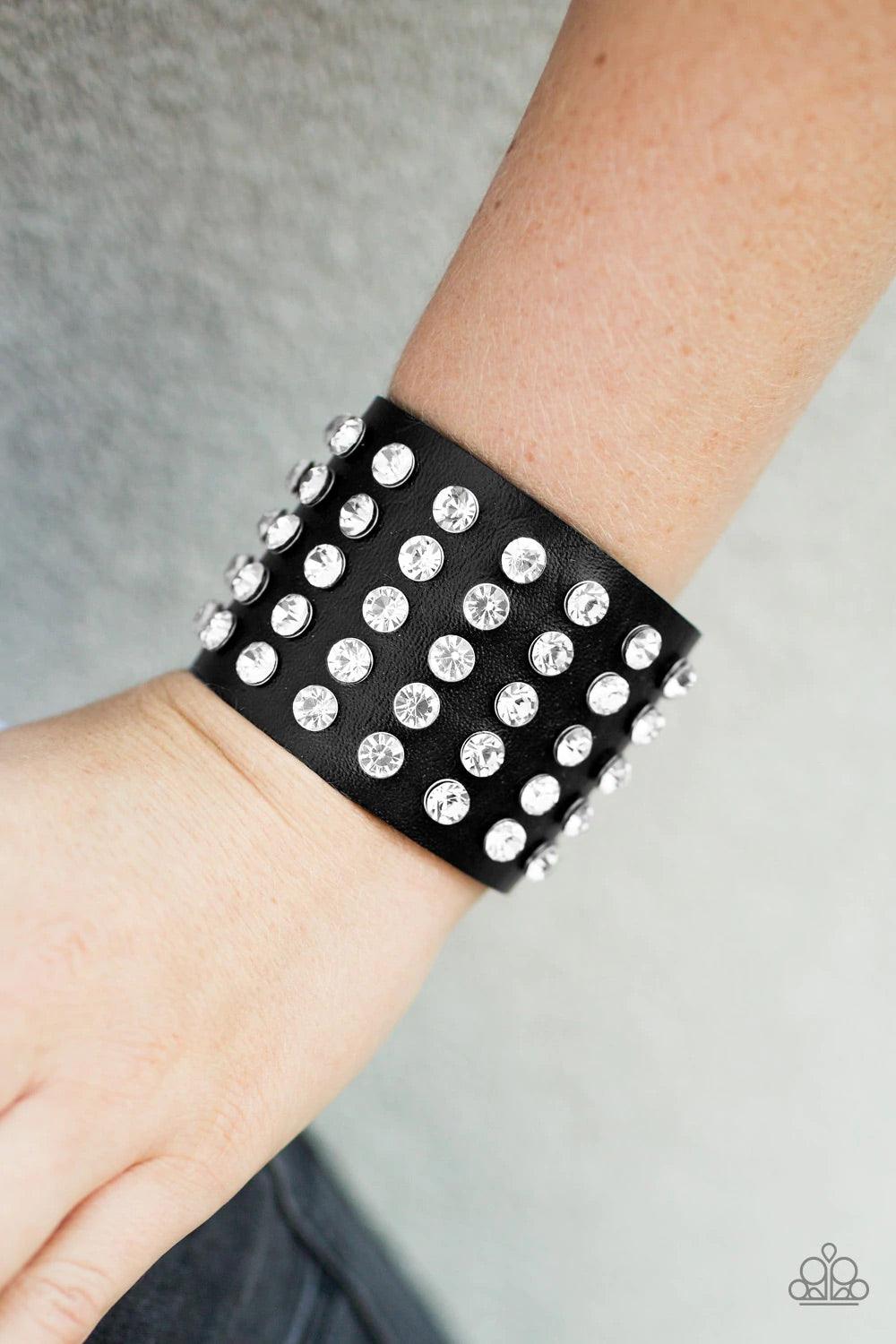 Paparazzi Accessories Mama Said Knock You Out - Black A chunky band of black leather is embellished with rows and rows of sparkling white rhinestones. With some urban edge and undeniable shimmer, the unified sparkle creates a bold centerpiece. Features an