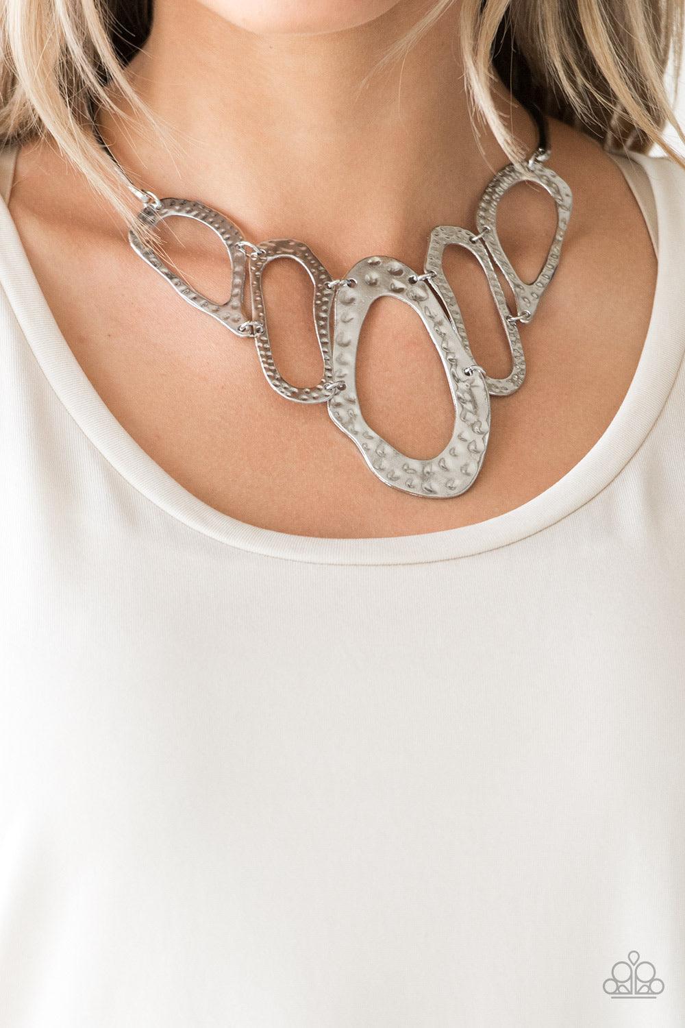 Paparazzi Accessories Prime Prowess - Silver Attached to two bent silver bars, delicately hammered asymmetrical silver hoops link below the collar for an edgy statement making look. Features an adjustable clasp closure. Sold as one individual necklace. In