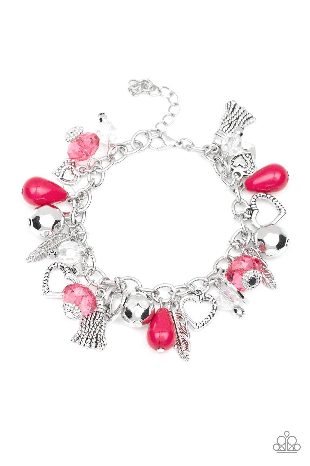 Paparazzi Accessories Completely Innocent - Pink A collection of faceted silver beads, polished pink beads, and pink and white crystal-like beads swing from a shimmery silver chain. An assortment of charms, including hearts, feathers, and tassels dangle b