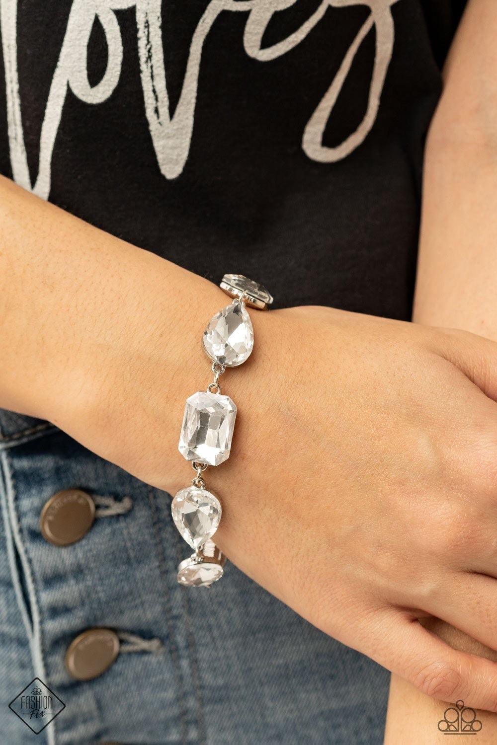Paparazzi Accessories Cosmic Treasure Chest - White A collection of oversized round, teardrop, and emerald cut rhinestones delicately link around the wrist, creating a blinding statement piece. Features an adjustable clasp closure. Sold as one individual