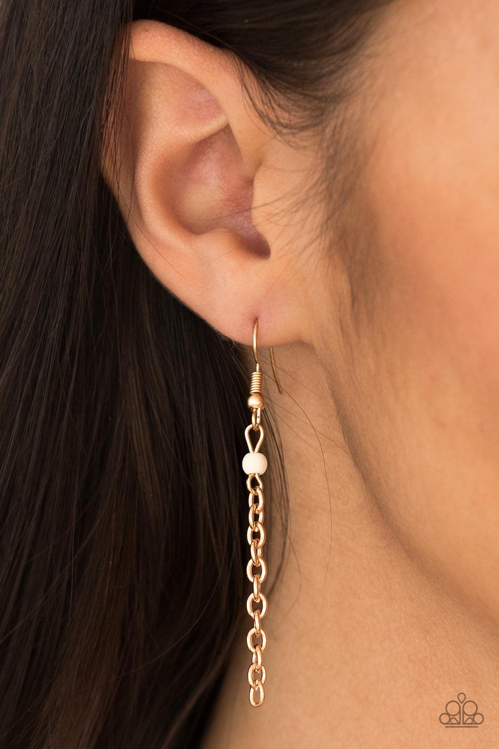 Paparazzi Accessories Runaway Rumba - Gold Glistening gold chains stream from the bottom of a shiny gold crescent, creating a bold tapered fringe down the chest. Dainty white stone beads sporadically trickle down the chains for a seasonal finish. Features