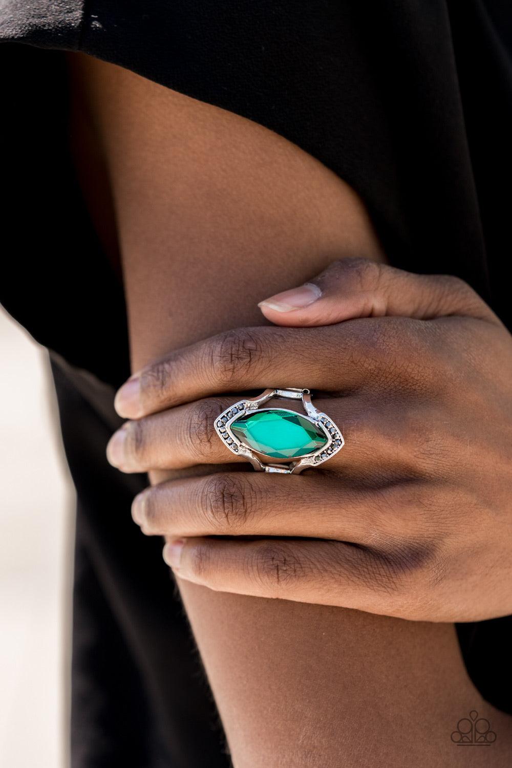 Paparazzi Accessories Leading Luster - Green Smoky hematite rhinestones are encrusted across the top and bottom angles of an airy silver frame. Featuring a faceted finish, a boldly cut green gem is nestled between the arcing bars for an edgy fashion. Feat