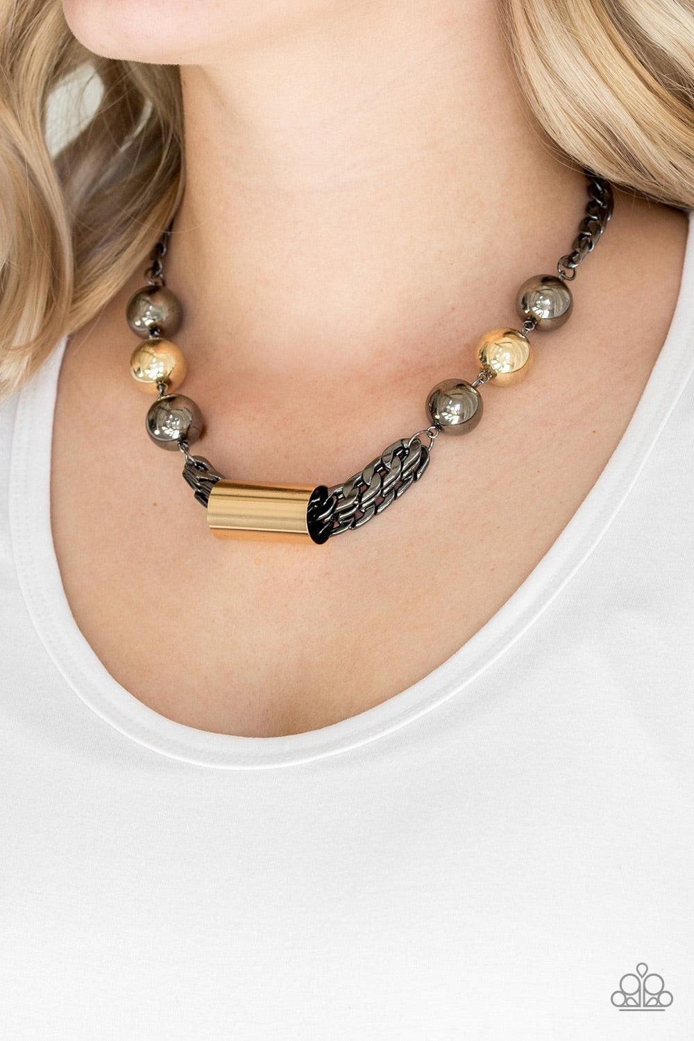 Paparazzi Accessories All About Attitude - Black Heavy gunmetal chains give way to sections of bold gold and gunmetal beads. A glistening gold accent slides along joined rows of heavy gunmetal chains, creating a spunky industrial centerpiece below the col