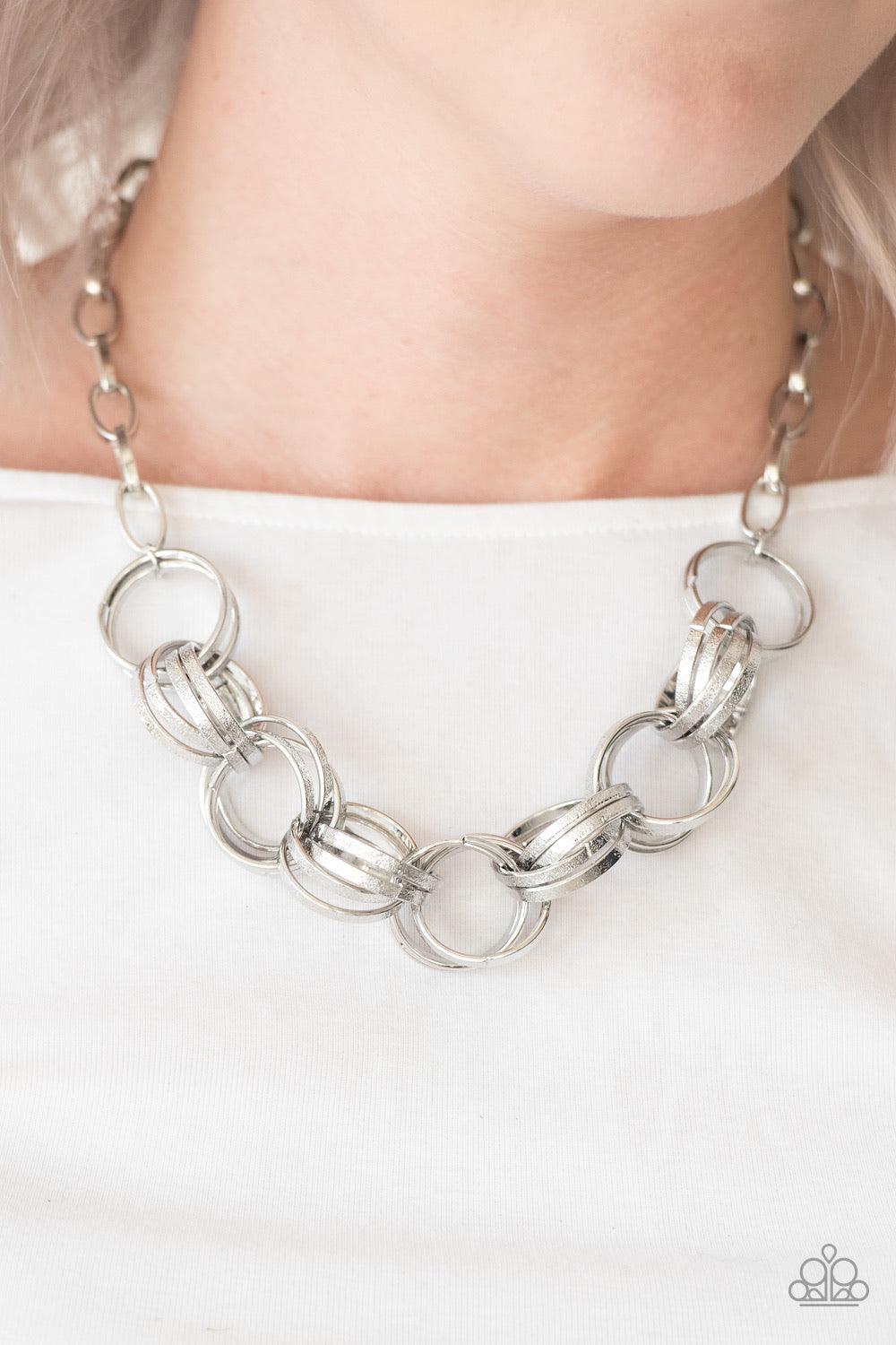 Paparazzi Accessories Statement Made - Silver Etched in light-catching shimmer, glistening silver rings link below the collar, connecting into a bold clustered fringe for a fierce industrial look. Features an adjustable clasp closure. Sold as one individu
