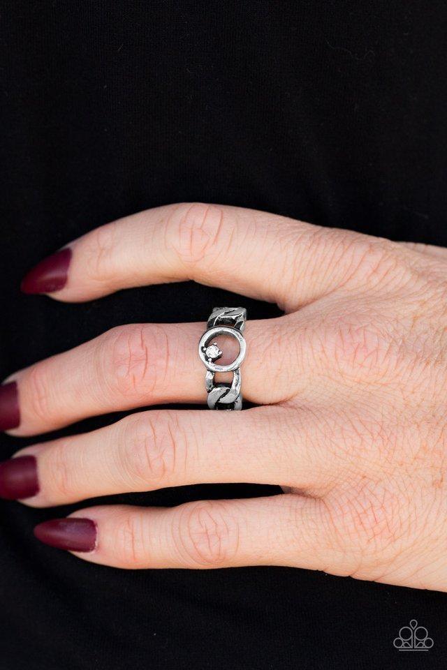 Paparazzi Accessories Rogue Sparkle - White Antiqued silver links join across the finger, creating an edgy band. A dainty white rhinestone asymmetrically dots the center link for a sassy finish. Features a dainty stretchy band for a flexible fit. Sold as