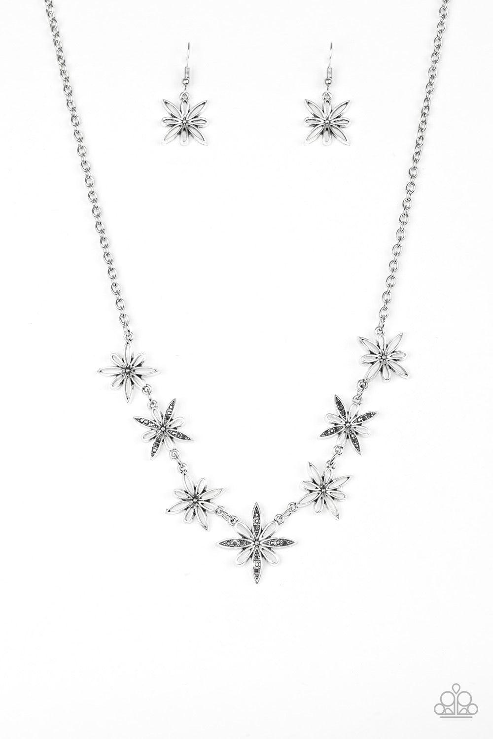 Paparazzi Accessories Decked Out In Daisies - Silver Airy silver floral charms link below the collar for a seasonal look. Dainty hematite rhinestones are encrusted along the petals of alternating floral frames for a glamourous finish. Features an adjustab