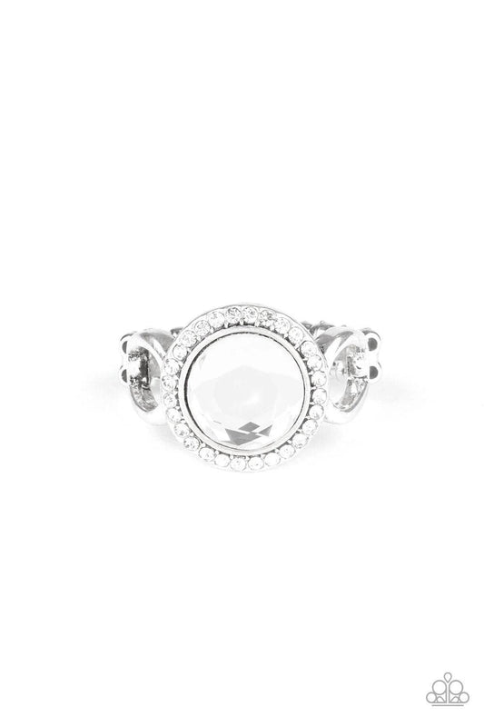 Paparazzi Accessories It’s Gonna GLOW! - White An oversized white gem is pressed into the center of a round silver frame encrusted in a ring of radiant white rhinestones for a regal flair. Features a dainty stretchy band for a flexible fit. Sold as one in