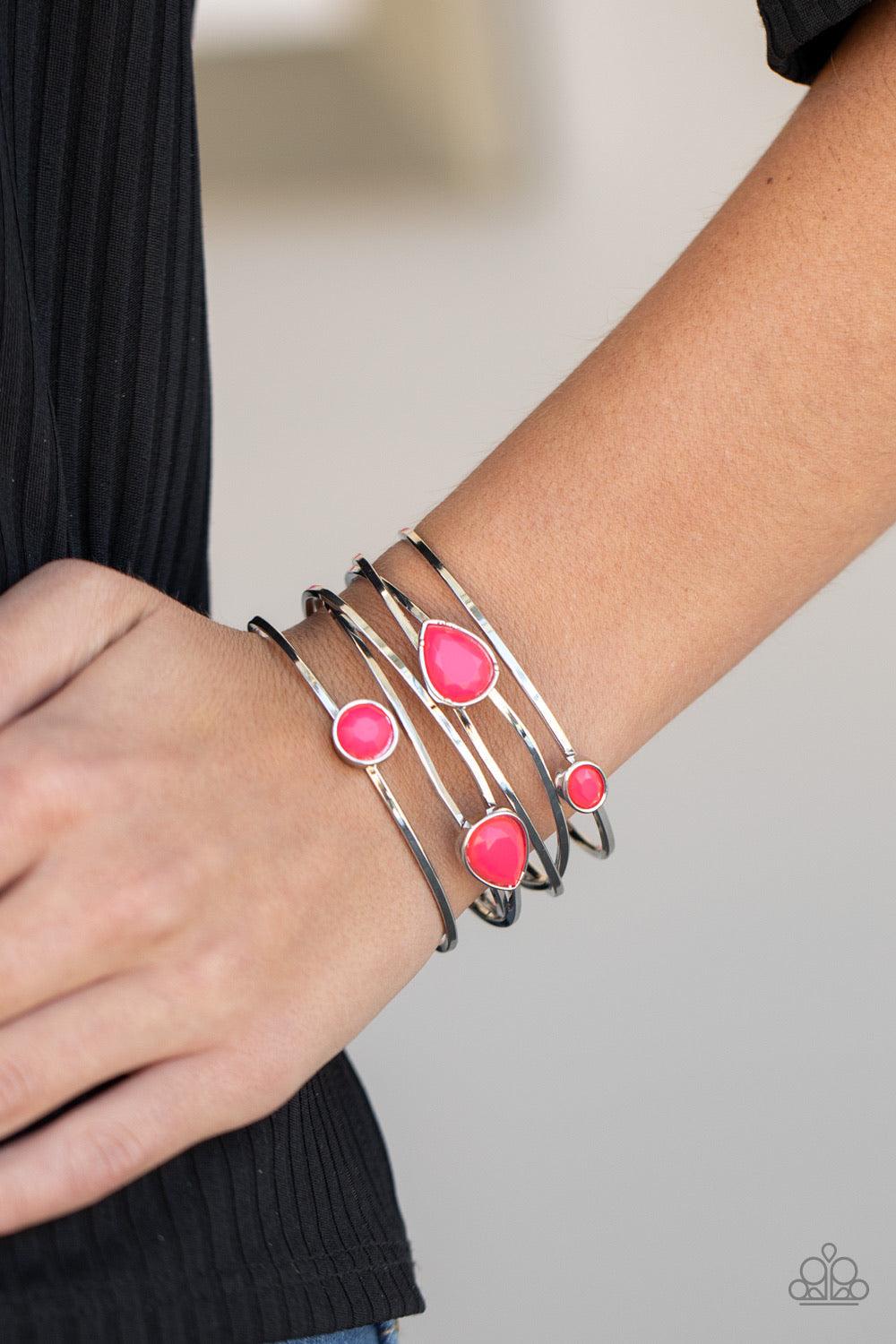 Paparazzi Accessories Fashion Frenzy - Pink Varying in shape, a neon collection of faceted pink beads haphazardly dot the tops of imperfect crisscrossing silver bars, coalescing into a colorfully retro cuff around the wrist. Sold as one individual bracele